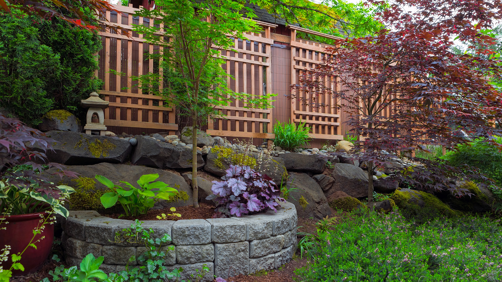 A garden with a rock wall and a bench